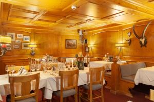 采尔马特耶格霍夫酒店的餐厅设有白色的桌椅和木墙