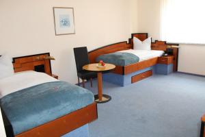 沃尔姆斯Heppenheimer Hof Hotel的一间卧室配有两张床和一张小桌子。