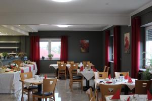 沃尔姆斯Heppenheimer Hof Hotel的一间配备有桌椅和红色窗帘的用餐室
