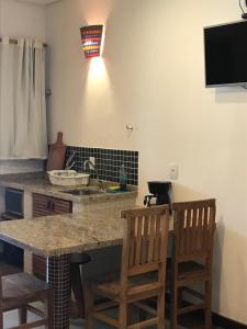 乌巴图巴Suites Grande Tenorio的厨房配有带2把椅子和水槽的台面
