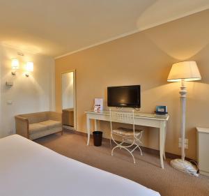 科内利亚诺Hotel Canon d'Oro的酒店客房配有一张床和一张书桌及一台电视