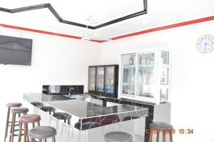 班珠尔Sukuta Nema Guest House的厨房设有带凳子和时钟的酒吧