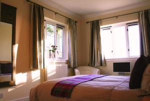 梅尔罗斯Broomfields Country House的一间卧室设有一张床和两个窗户。