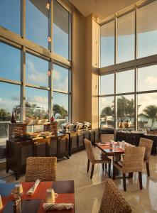 迈阿密海滩阳光岛艾美海滩度假村 的餐厅设有桌椅和大窗户。