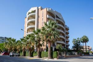 阿尔巴·阿德里亚蒂卡Residence Torre Del Mar的一座高大的建筑,前面有棕榈树