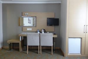 卡斯塔莫努穆特威利酒店的配有一张桌子、两把椅子和一台电视的房间