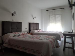 莱佩拉诺里亚酒店的一间卧室设有两张床、一张桌子和一个窗口