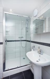 牛津松柏宾馆的一间带玻璃淋浴和水槽的浴室