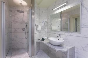 加尔达湖滨托奈利克里斯塔尔皇宫酒店的白色的浴室设有水槽和淋浴。