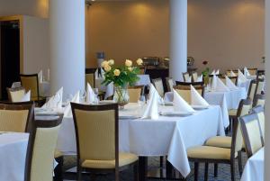 罗兹国宾中心酒店的用餐室配有白色的桌椅和鲜花