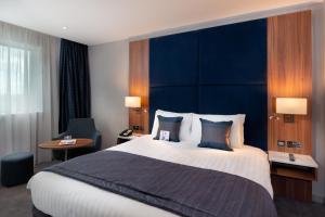 希灵登伦敦希思罗机场皇冠假日酒店第四航站楼店的一间卧室配有一张大床和蓝色床头板