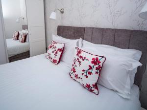 哈罗盖特Regent Penthouse的一张带红色和白色枕头及镜子的床