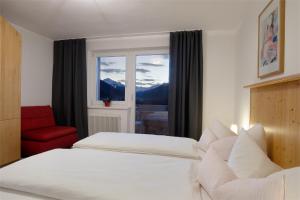 因斯布鲁克蒂罗尔阿尔卑霍夫公寓酒店的一间卧室配有一张床、一张红色椅子和一个窗户