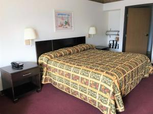 阿尔伯克基American Inn & Suites的酒店客房配有一张床、一张桌子和一部电话