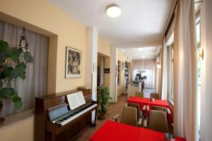 西尼加利亚Albergo Moretti的一间设有钢琴、桌子和椅子的客房