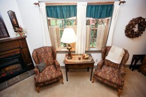 尤宁敦Watson Estate BnB & Deer Creek Winery的客厅配有两把椅子、一张桌子和壁炉