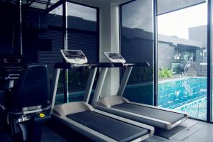 怡保M Roof Hotel & Residences的健身房设有两个跑步机,毗邻游泳池