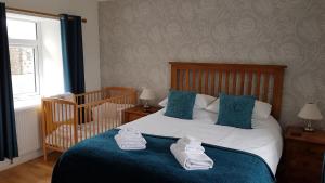 FlashaderCottages Lyndale Farm的一间卧室配有婴儿床和一张带毛巾的床。