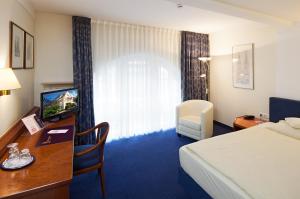 科隆维克托亚酒店的酒店客房配有一张床和一张书桌及一台电视