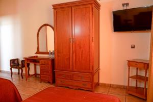 圣埃伦娜阿尔夫恩索八世酒店的一间卧室配有大型木制橱柜和一张书桌
