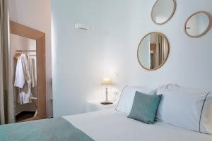 萨鲁米科诺斯色彩奢华公寓式酒店的一张带蓝色枕头和镜子的白色床