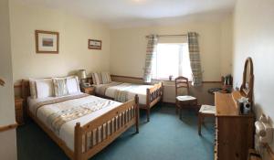 FahaO'Connors Guesthouse的一间卧室设有两张床、一张桌子和一个窗口。
