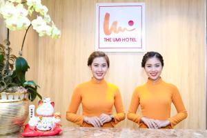胡志明市The Umi Hotel的两个穿着橙色毛衣的女人站在桌子旁