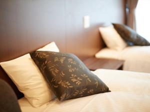 那霸Creass Hotel Tsubogawa Marche的床上有棕色枕头