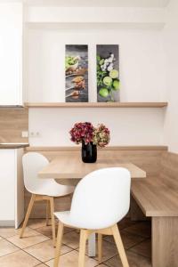 博尔扎诺Pixner Apartments的餐桌,带两把椅子和花瓶