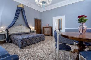 威尼斯梅佐波卓酒店的一间卧室配有一张床和一张桌子,上面有花瓶