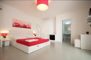 佩斯科勒海滨Hotel Beach Salento的一间白色卧室,配有红色的床和一间浴室