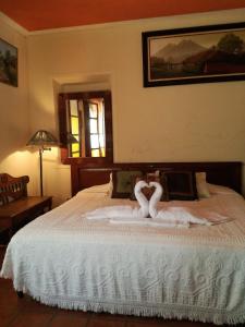 危地马拉安地瓜Posada San Sebastian的一间卧室配有一张带两个天鹅的床