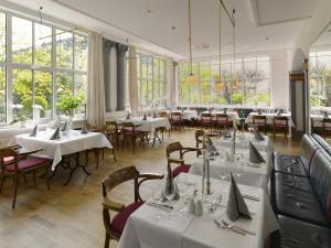 魏玛奥古斯特开森瑞酒店的餐厅设有白色的桌椅和窗户。