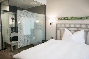 圣加仑Hotel Metropol的卧室配有白色的床和玻璃墙