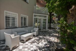 米兰马瑞提那Villa Norma的庭院配有白色的椅子、沙发和窗户。