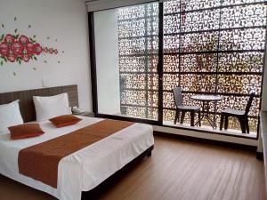 梅尔加Suite Sumapaz Hotel的一间卧室配有一张床、一张桌子和一个大窗户