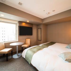 东京Super Hotel Premier Ginza的酒店客房设有床、桌子和窗户。