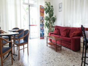 里米尼荣科尼酒店的客厅配有红色的沙发和桌椅