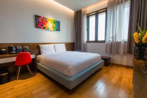 岘港Icity Villa Riverfront Danang的一间卧室配有一张床、一张桌子和一把红色椅子