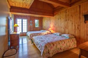 萨格奈Le Cent的配有木墙和木地板的客房中的两张床
