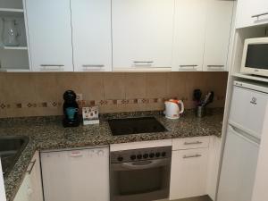马贝拉Mariana & Sirus´ Home的厨房配有白色橱柜、水槽和微波炉