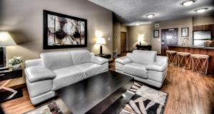 大草原城Grand Inn & Residence- Grande Prairie的客厅配有2把白色椅子和桌子