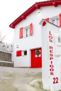 安普埃罗Los Respigos de la Pradera的白色的建筑,有红色的门和标志
