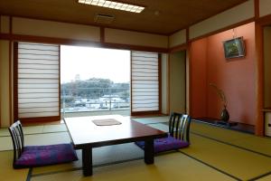 平戸市旗松亭日式旅馆的一间带桌椅和窗户的用餐室