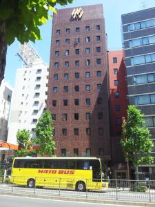 东京东京银座首都酒店茜馆(Ginza Capital Hotel Akane)的停在高楼前的黄色巴士