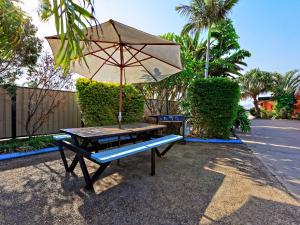 班达伯格班达伯格里维埃拉汽车旅馆的一张带雨伞和长凳的野餐桌