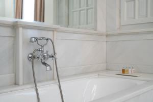 雅典贵族套房公寓式酒店的浴室设有带淋浴喷头的浴缸。