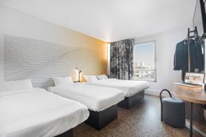 里昂B&B HOTEL Lyon Centre Part-dieu Gambetta的酒店客房设有两张床和窗户。