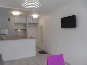 米尼赞海滩La Forêt 5的厨房配有紫色椅子,墙上配有电视