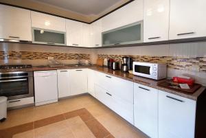 斯兰默多瓦Vila Moldavia Class的厨房配有白色橱柜和微波炉